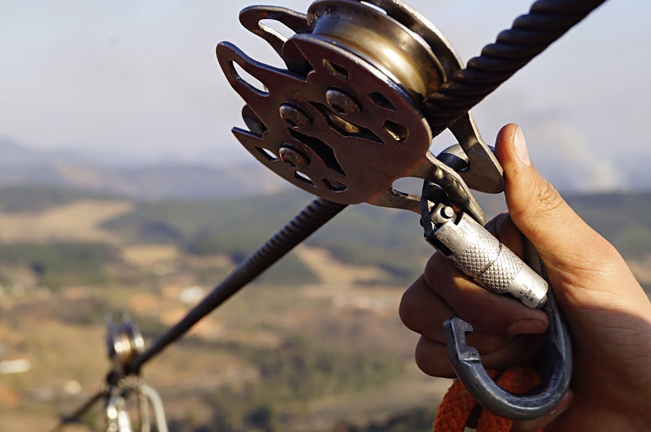 Visitante descendo pela maior tirolesa das Américas em Pedra Bela, São Paulo, com vistas deslumbrantes da natureza ao redor.