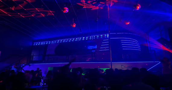 Pista de dança lotada do Enigma Club em São Paulo, com iluminação temática e decoração inspirada em navio.
