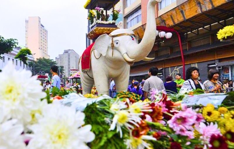 Cortejo do Hana Matsuri com um elefante branco e participantes em trajes tradicionais na Praça da Liberdade