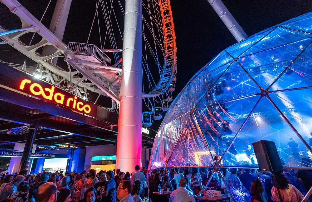 Pessoas desfrutando do Wine & Jazz Sessions em São Paulo, com vinhos e apresentação de jazz ao fundo.