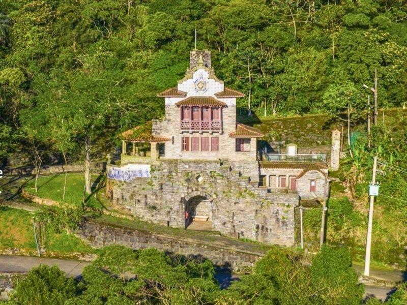 Vista panorâmica da Serra do Mar com o casarão histórico e café 1922 em primeiro plano