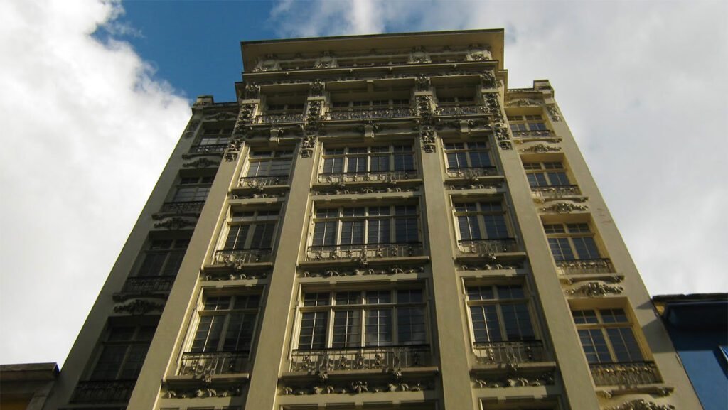 Fachada do Edifício Guinle, primeiro prédio de sete andares de São Paulo, destacando seu estilo Art Nouveau e elementos decorativos.