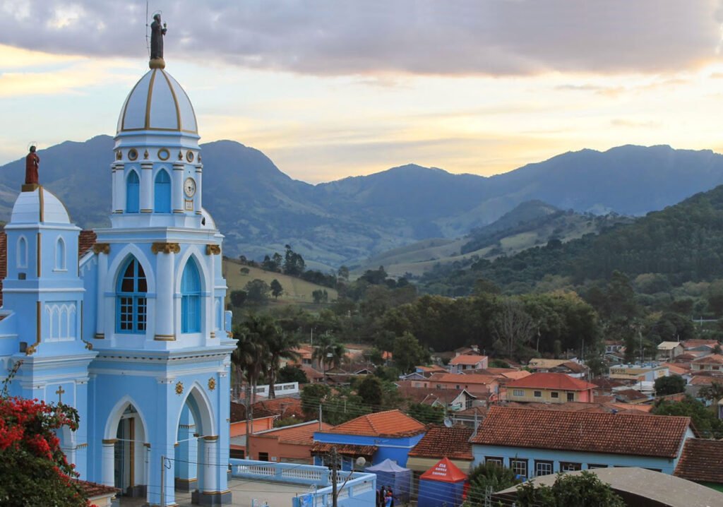 Vista panorâmica da Pedra do Baú em São Bento do Sapucaí, com montanhas e vegetação exuberante ao fundo.