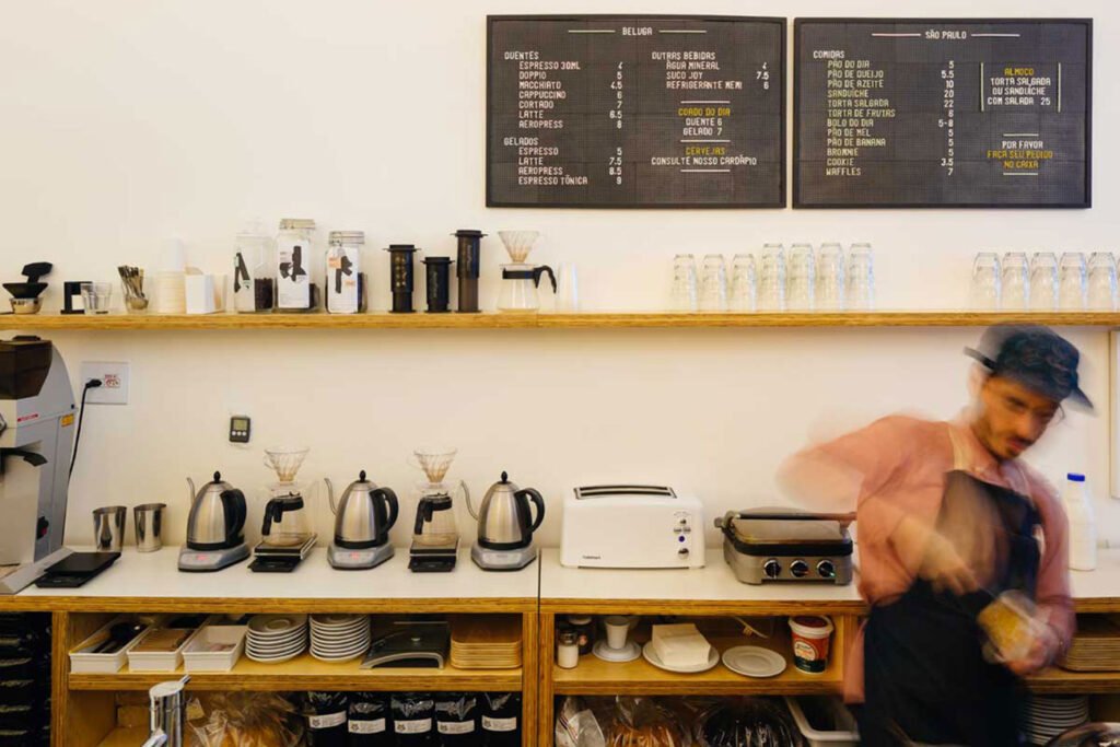 Uma xícara de café servido no Takko Café, em São Paulo, com grãos de café ao fundo.