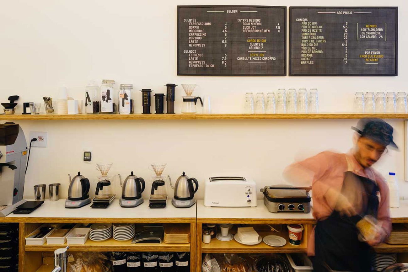 Uma xícara de café servido no Takko Café, em São Paulo, com grãos de café ao fundo.