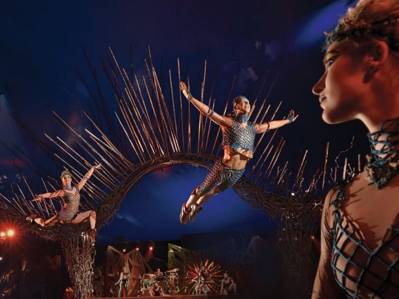 Cenografia vibrante da instalação do Cirque du Soleil na Avenida Paulista com acrobatas e elementos decorativos coloridos