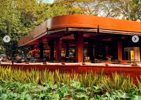 Praça de um parque em São Paulo com quiosques gastronômicos e pessoas interagindo