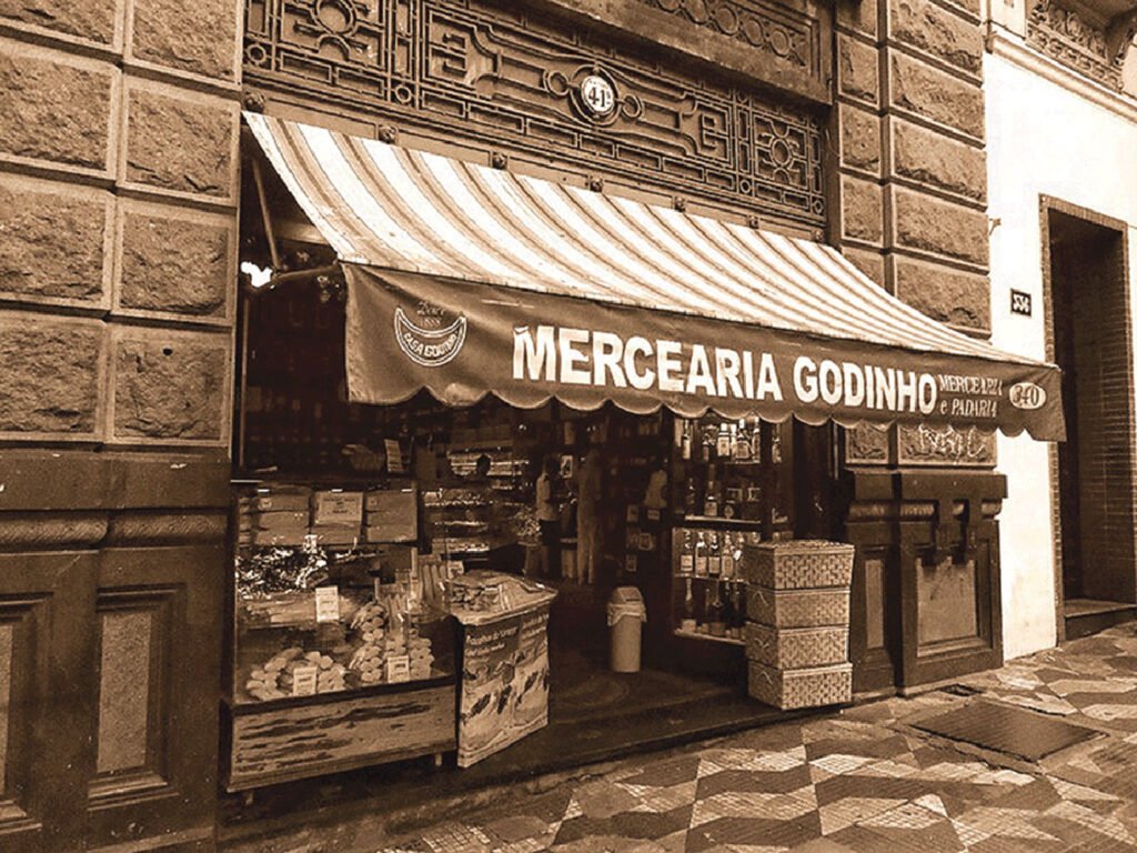Interior da Mercearia Casa Godinho em São Paulo, mostrando prateleiras de produtos e um ambiente nostálgico.