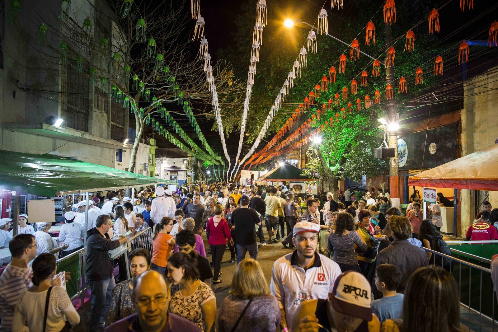 Festa da Achiropita em São Paulo com barracas de comida e pessoas celebrando