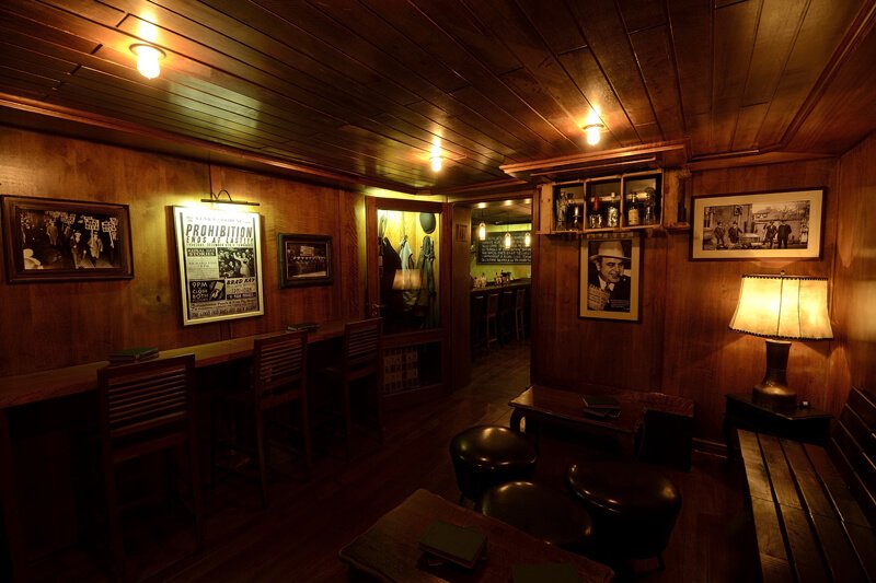 Interior do Frigobar, um bar speakeasy em São Paulo, com iluminação suave e decoração nostálgica