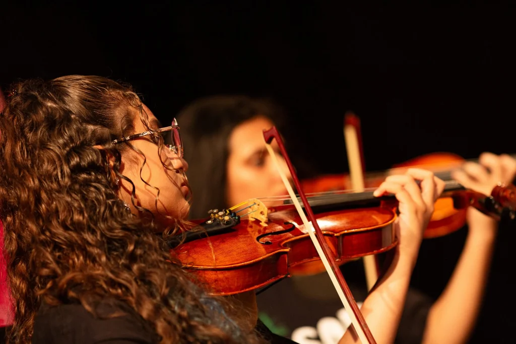 Crianças e adultos participando de aulas de música do programa GURI em São Paulo
